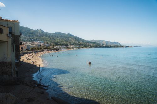 Free Idyllic coastal scene with a beach, mountains, and clear blue sea under a sunny sky. Stock Photo