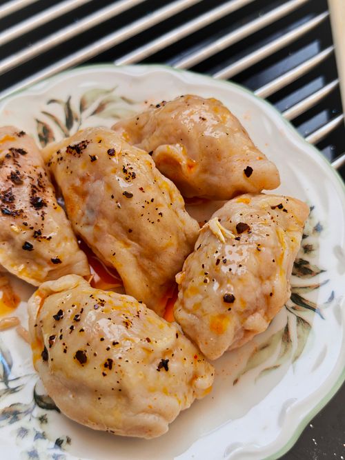 Free Appetizing steamed dumplings drizzled with chili oil served on a decorative plate, perfect for culinary themes. Stock Photo