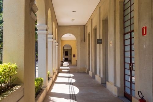 Free Sunlit corridor with archways casting shadows on a sunny day. Stock Photo