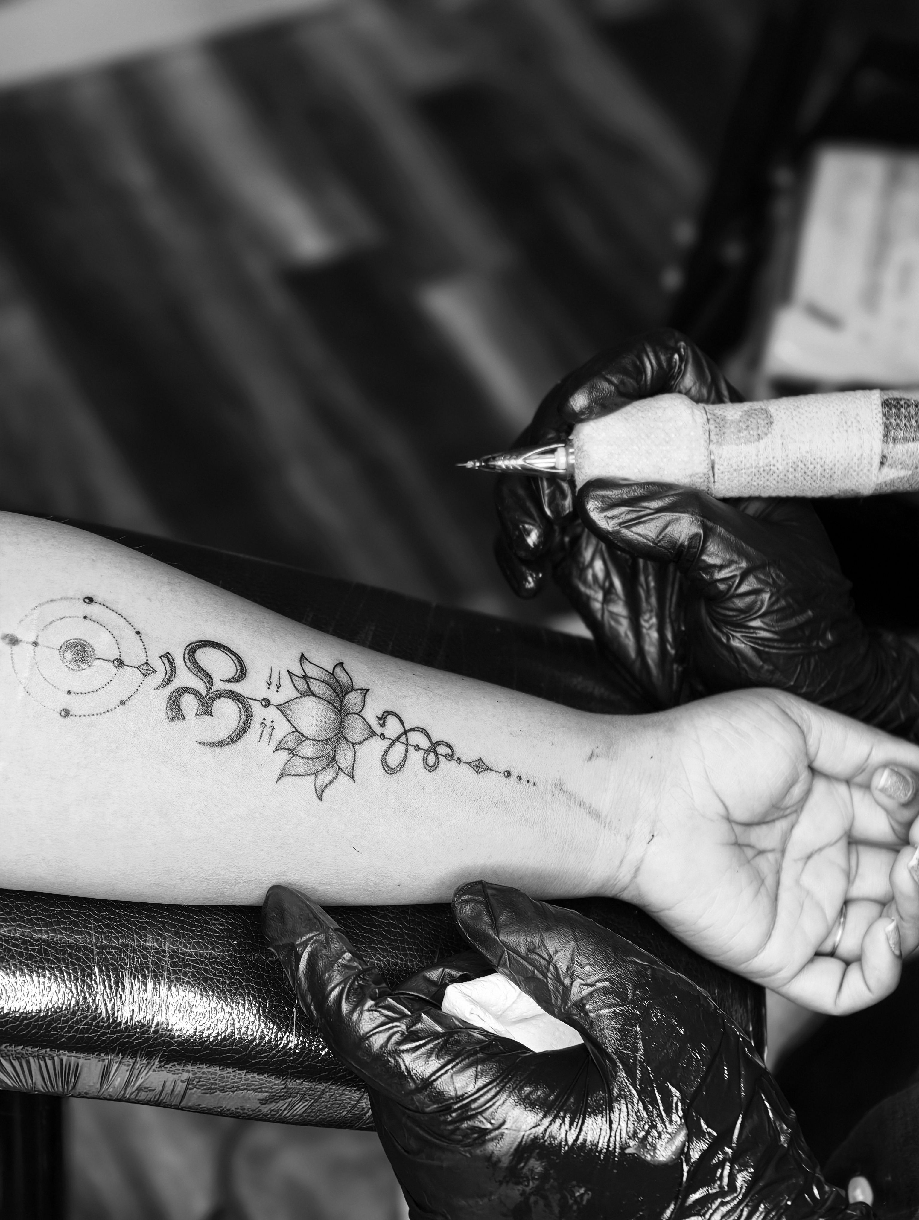 Tattoo artist creating a Hindu spiritual symbol tattoo with lotus design