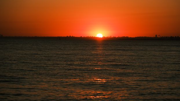 A breathtaking sunset over the ocean with vivid orange hues reflecting on the water.