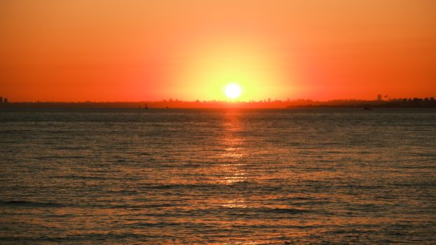 A breathtaking sunset over the ocean with a silhouette of a distant skyline.