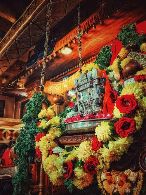 Free Colorful garlands decorate a religious idol inside an Indian temple, showcasing vibrant cultural ornamentation. Stock Photo