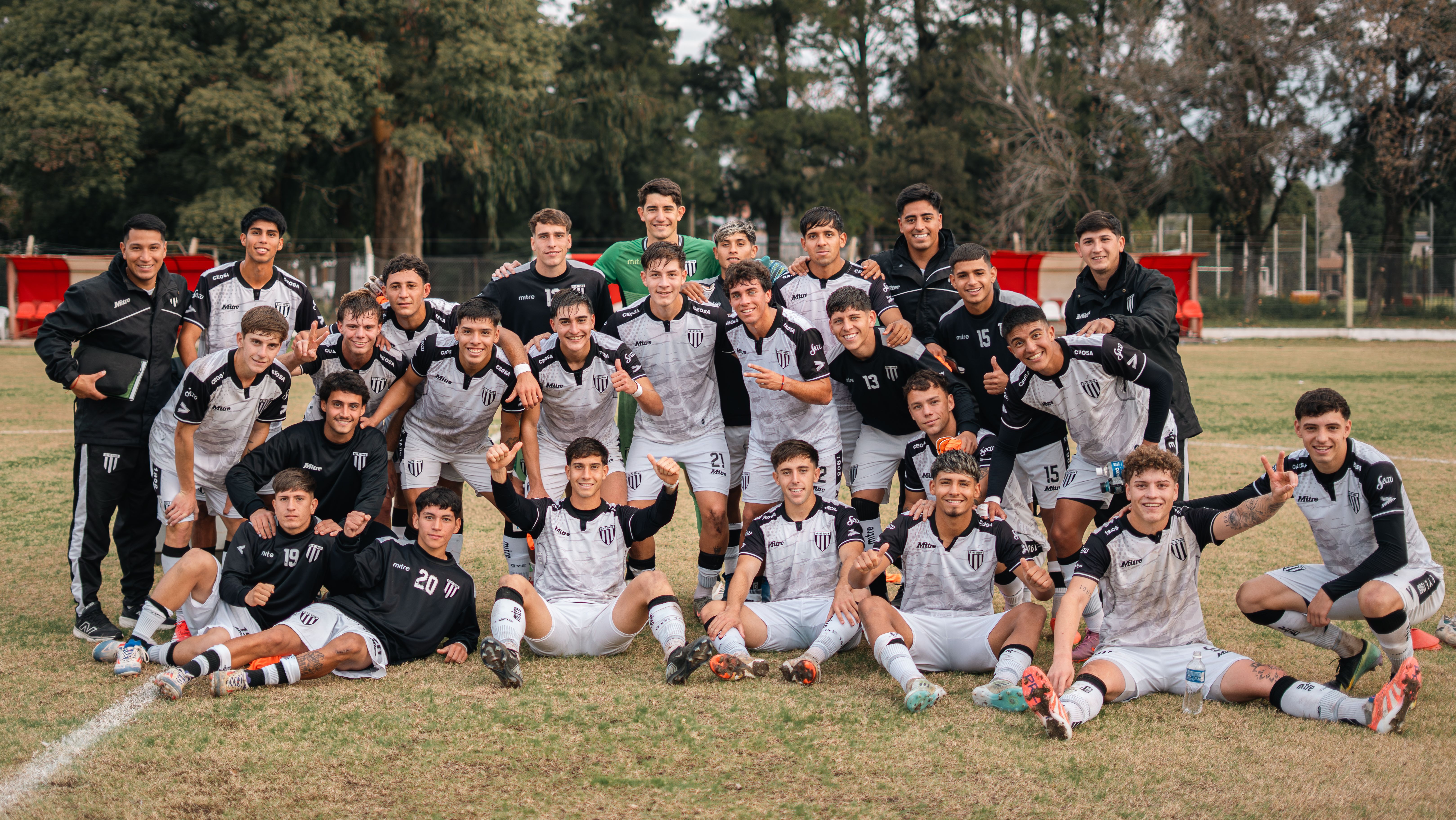 Youth soccer team posing on field after a victorious match, displaying team spirit.