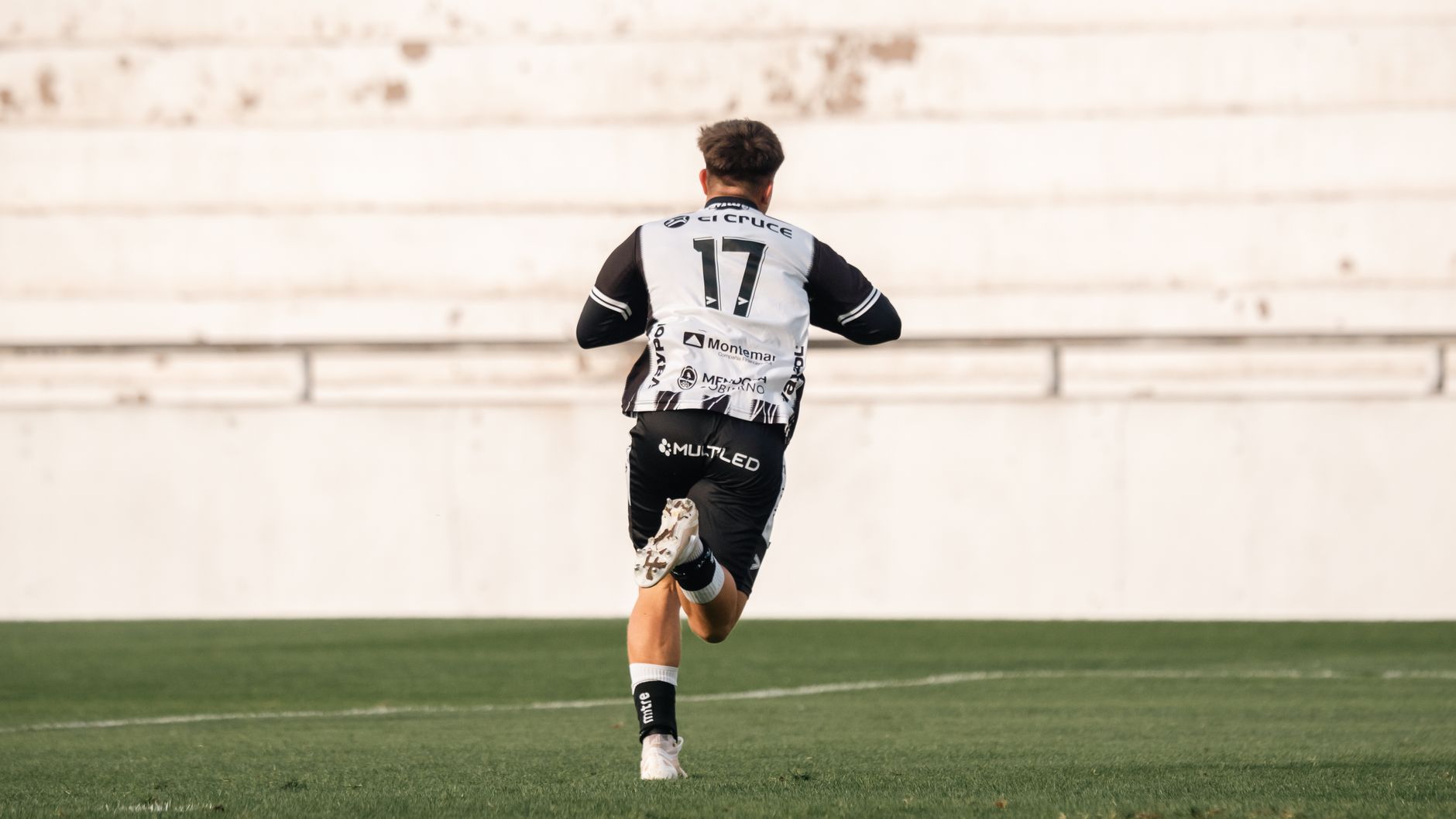 Soccer player in black and white uniform running across the field during a game.