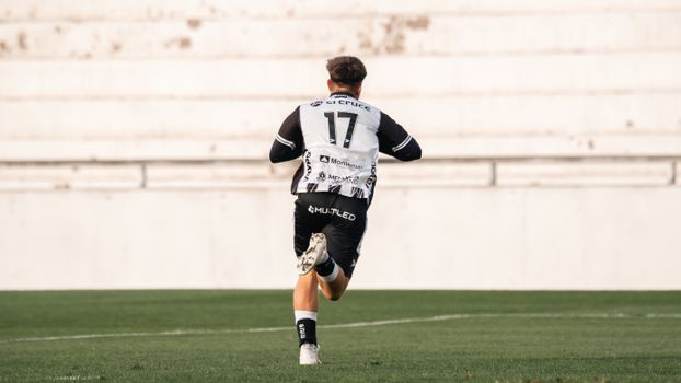 Soccer player in black and white uniform running across the field during a game.