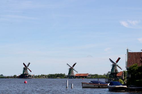 Free Scenic view of traditional windmills and boats on the river at Zaans Schans, Netherlands. Stock Photo
