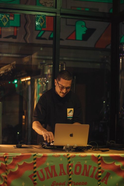Free DJ performing live set on laptop at a nightclub with vibrant lighting and decor. Stock Photo
