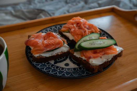 Plate of tasty smoked salmon sandwiches with cream cheese and cucumber. Perfect breakfast or brunch option.