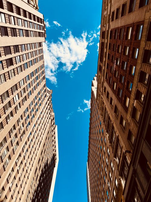 Free Stunning upward perspective of urban skyscrapers against a vibrant blue sky with white clouds in New York City. Stock Photo