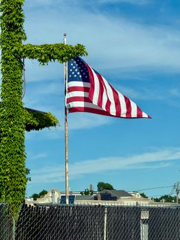 United States flag waving against a blue sky, symbolizing patriotism and freedom.