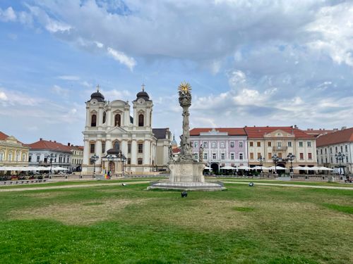 Free View of Union Square featuring the Holy Trinity Monument in Timișoara, Romania's vibrant cityscape. Stock Photo