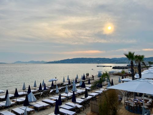 Free A tranquil beach scene at sunset with sunbeds and umbrellas overlooking the calm sea. Stock Photo