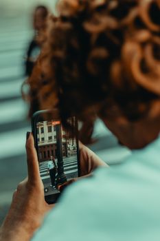 A close-up view of someone photographing an urban street scene with a smartphone.