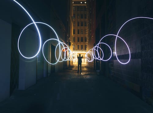 Силуэт человека, делающего круги с фонариком на темной улице