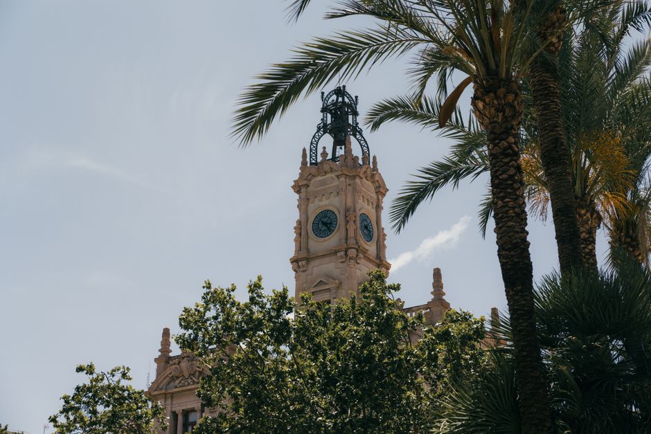 Torre del reloj histórica enmarcada por exuberantes palmeras en Valencia, España.