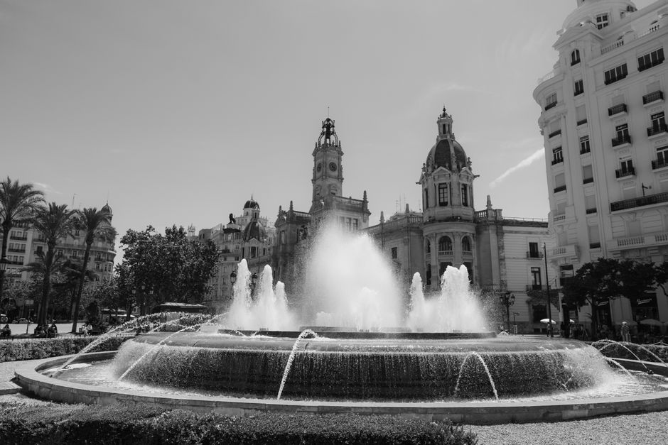 Captura elegante en blanco y negro de la Plaza del Ayuntamiento en Valencia, España, con una fuente central.