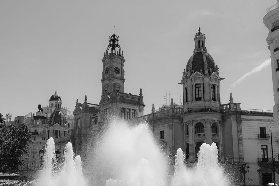 Fotografía en blanco y negro del Ayuntamiento de Valencia con una fuente, que captura la arquitectura clásica europea.
