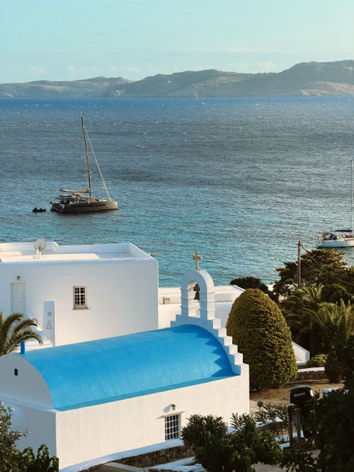 Free Charming white chapel with blue dome by the sea in a Greek island setting. Stock Photo