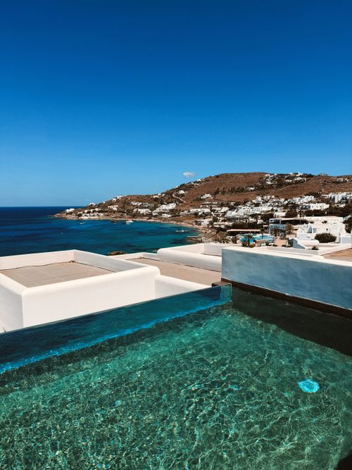 Free Stunning view of Mykonos coastline with turquoise water and an infinity pool under a clear blue sky. Stock Photo