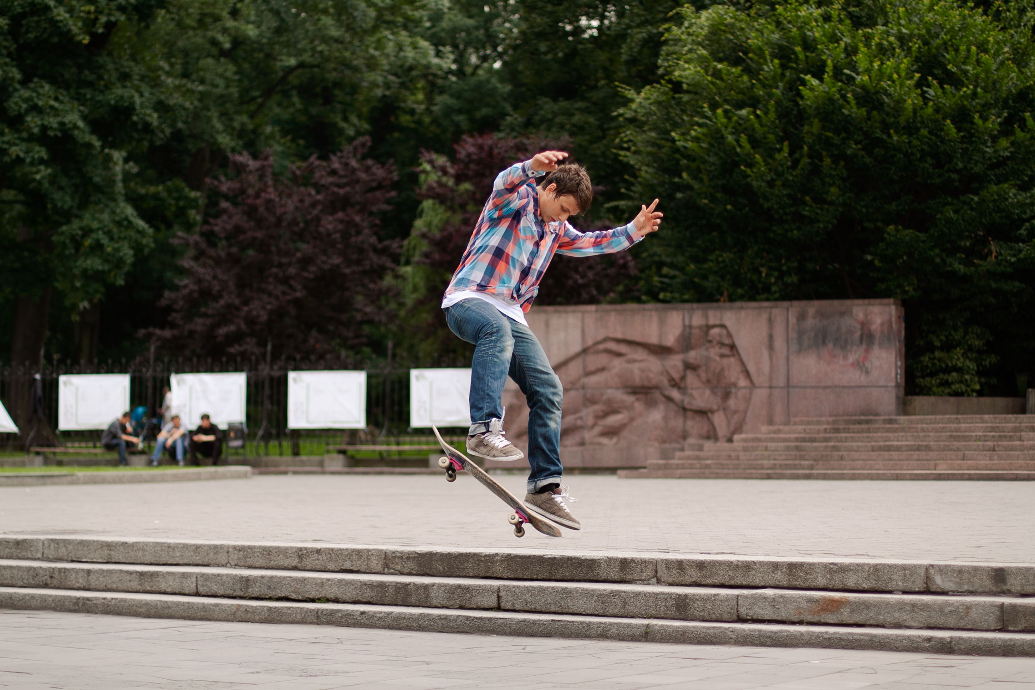 A teenage boy performing a skateboard trick in an outdoor park in Lviv, Ukraine.