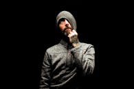 一个在黑暗背景下沉思的大胡子男人特写，他穿着毛衣，没戴帽子