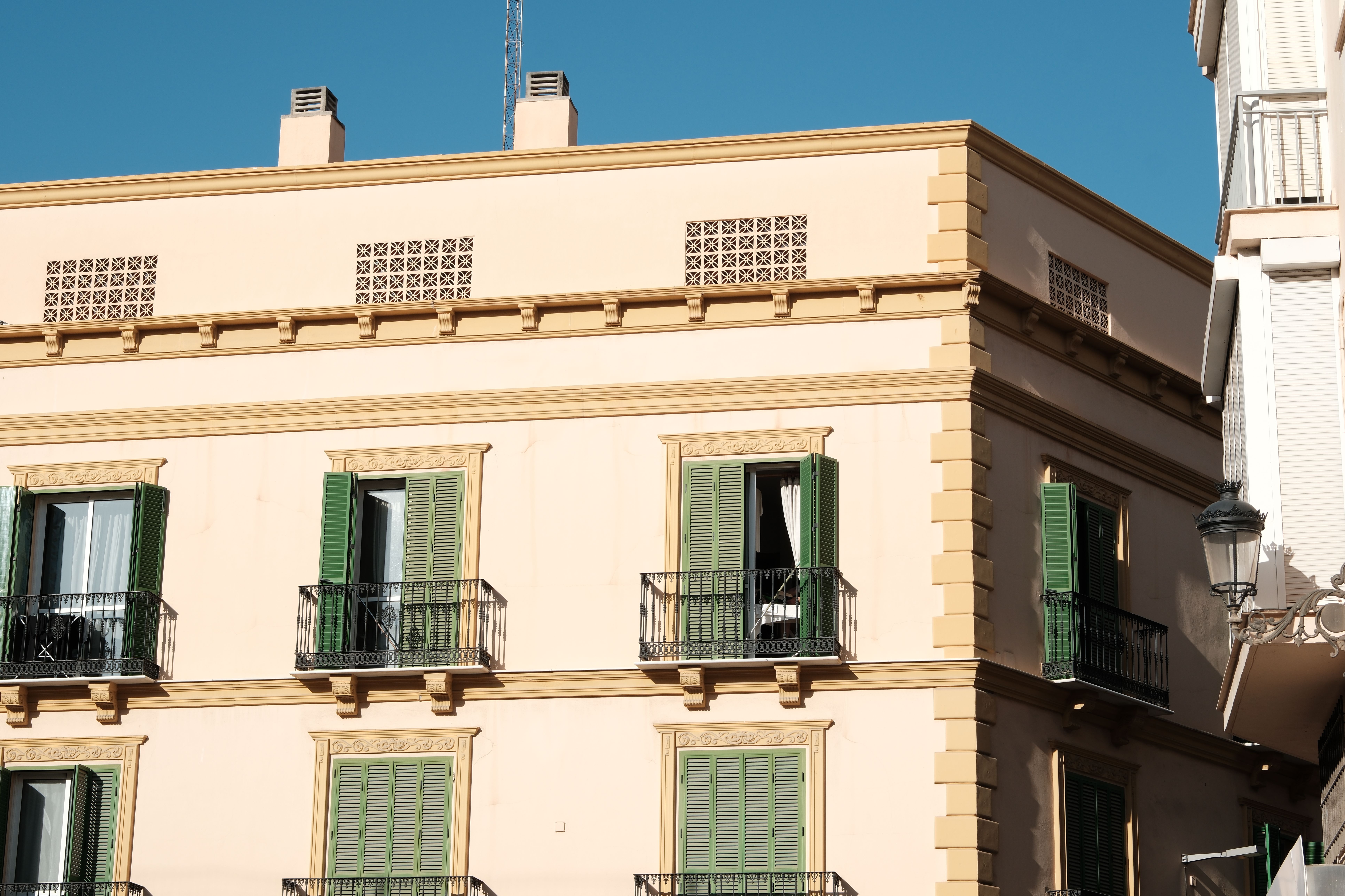 Elegant Spanish architecture with green shutters on a sunny day.