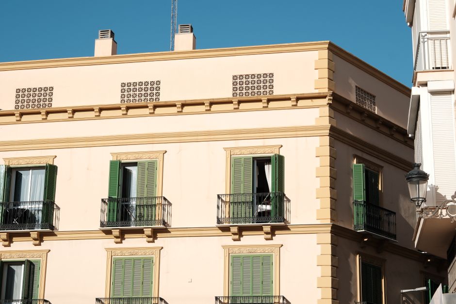 Elegant Spanish architecture with green shutters on a sunny day.