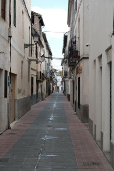 Charming narrow street in Spain's historic district, lined with rustic buildings.