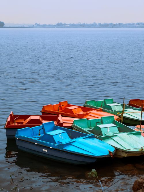 Free Vibrant pedal boats floating on a serene lake under a clear sky, ideal for summer leisure. Stock Photo