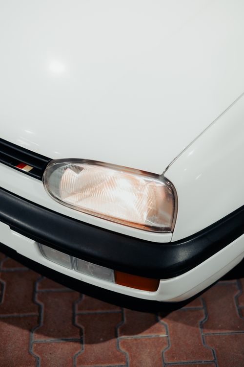 Free Detailed view of a vintage car's headlight and bumper with a reflective surface. Stock Photo