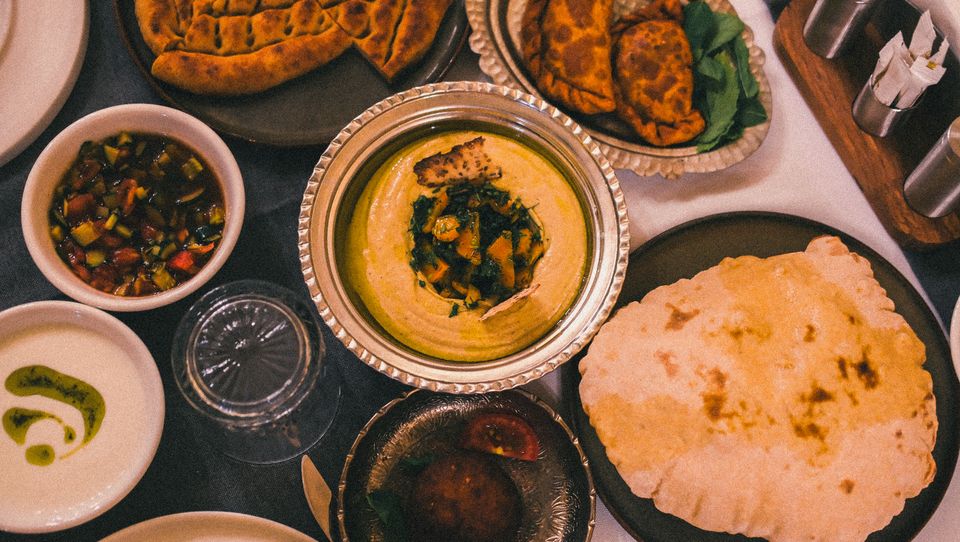 Overhead spread of flatbreads, hummus and mezze dips — photo by Zeynep Hız on Pexels
