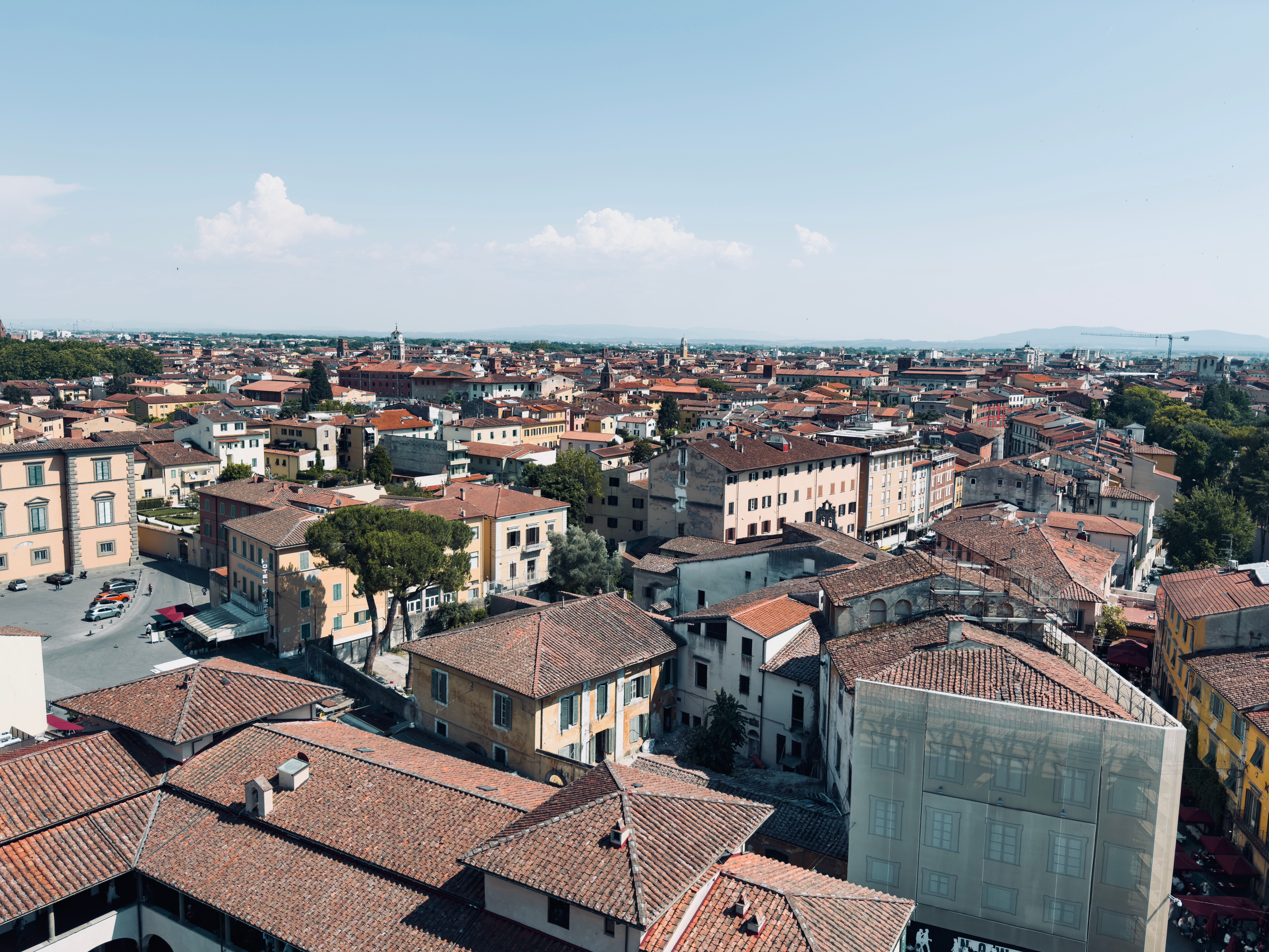 Scenic aerial view of Pisa's terracotta rooftops under a clear blue sky, capturing the essence of Italian architecture.