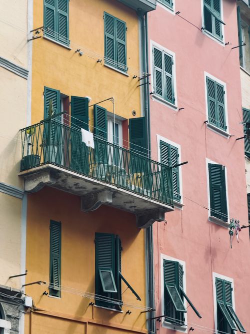 Free Vibrant pastel building facade in Italy with green shutters and balcony. Stock Photo