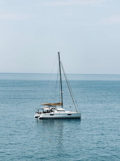 Free A solitary catamaran sails peacefully on the Ligurian Sea, capturing the essence of tranquil maritime travel. Stock Photo
