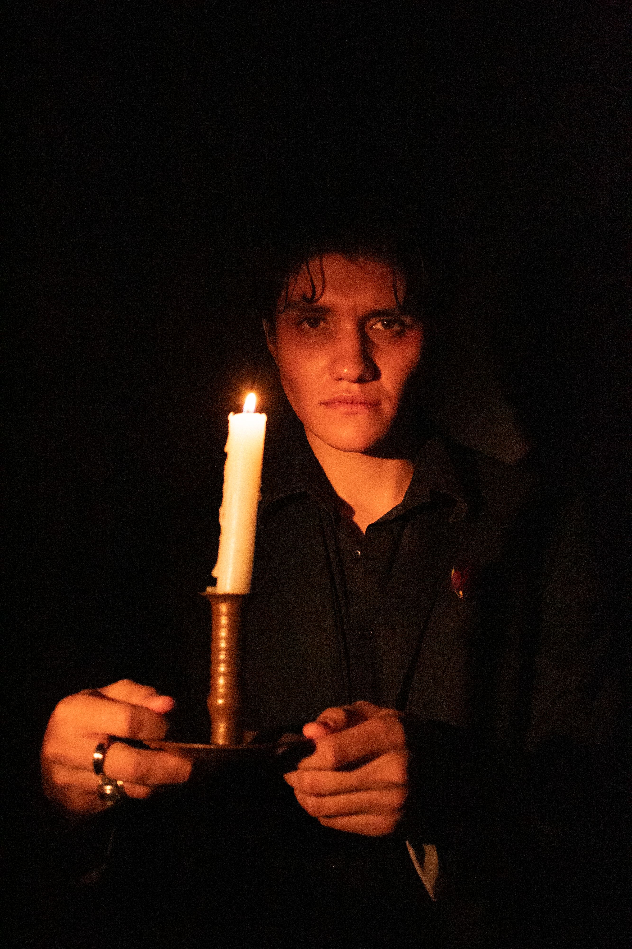 Portrait of a person holding a candle, highlighting dramatic shadows and a mysterious atmosphere.
