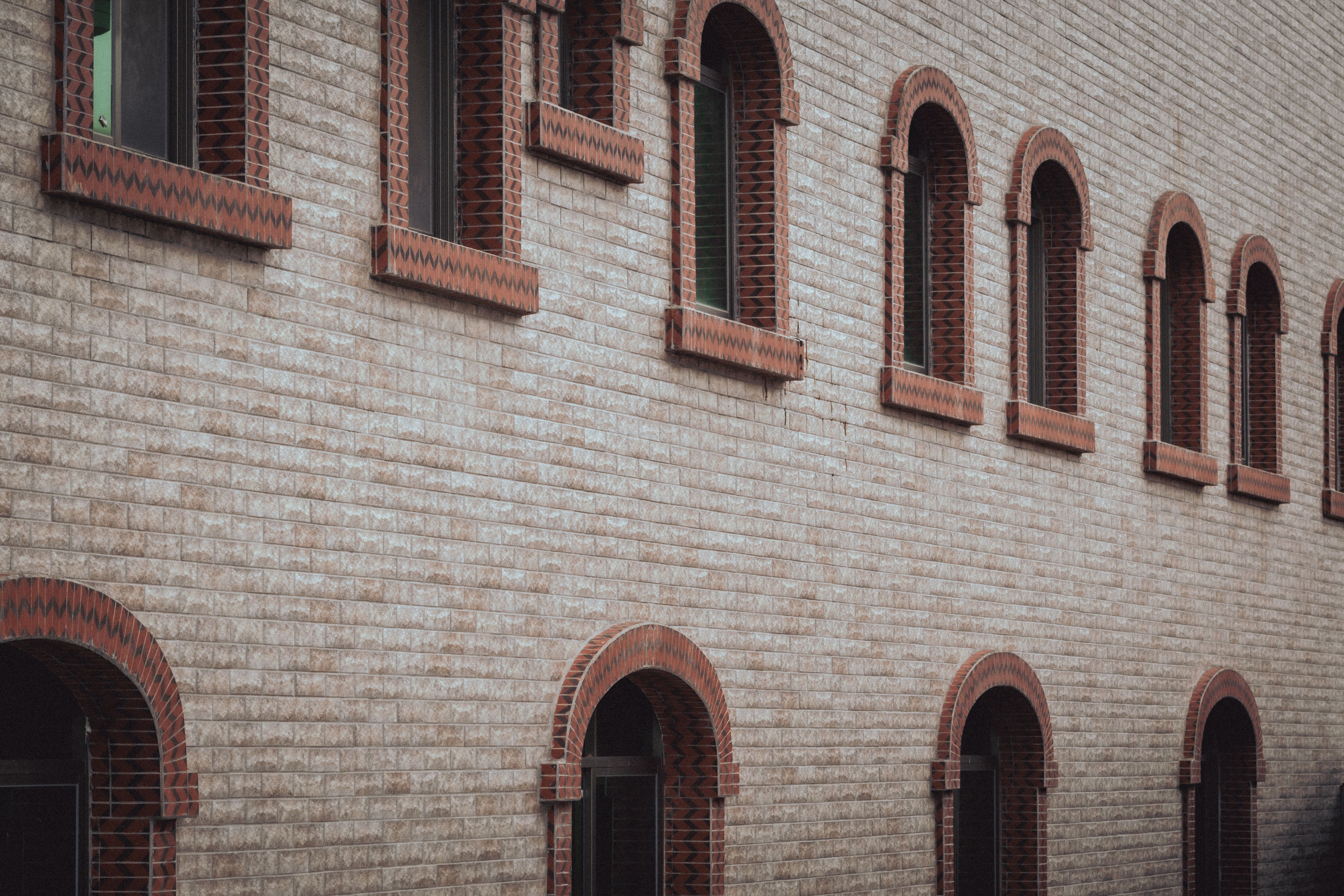 Exterior view of a brick building featuring symmetrical arched windows in a classic style.