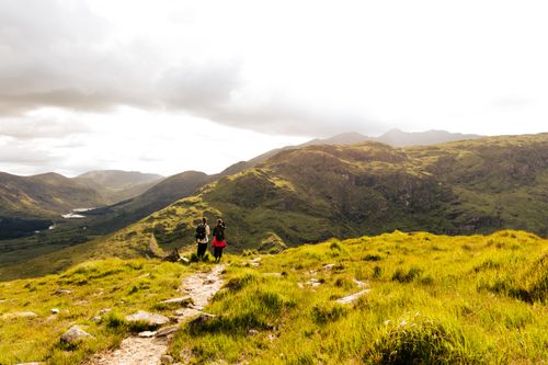 Free Two hikers explore a picturesque trail in Killarney, Ireland, surrounded by lush green hills. Stock Photo