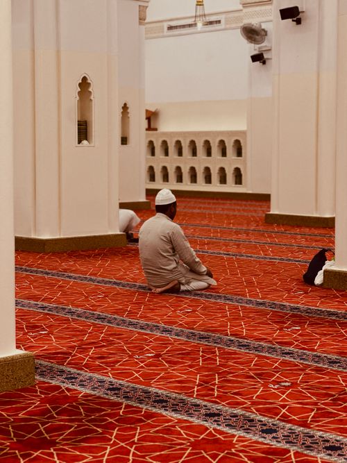 Free A person in quiet contemplation inside the beautiful architecture of a Madinah mosque. Stock Photo