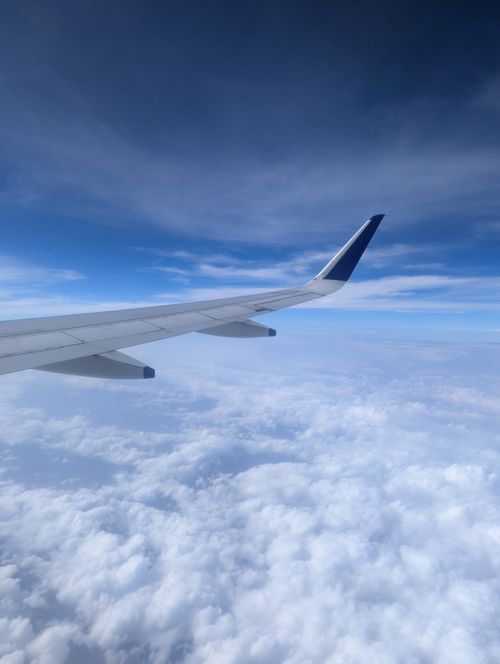 Free Blue skies and fluffy clouds seen from an airplane wing's perspective. Stock Photo
