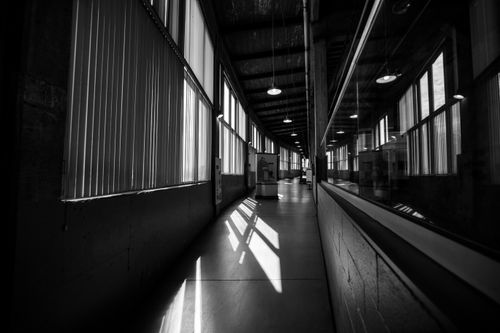 Free A black and white photo of an industrial corridor with dramatic lighting and reflections. Stock Photo
