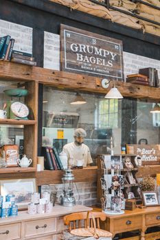 Interior of a cozy bagel shop featuring wooden decor and a baker at work.