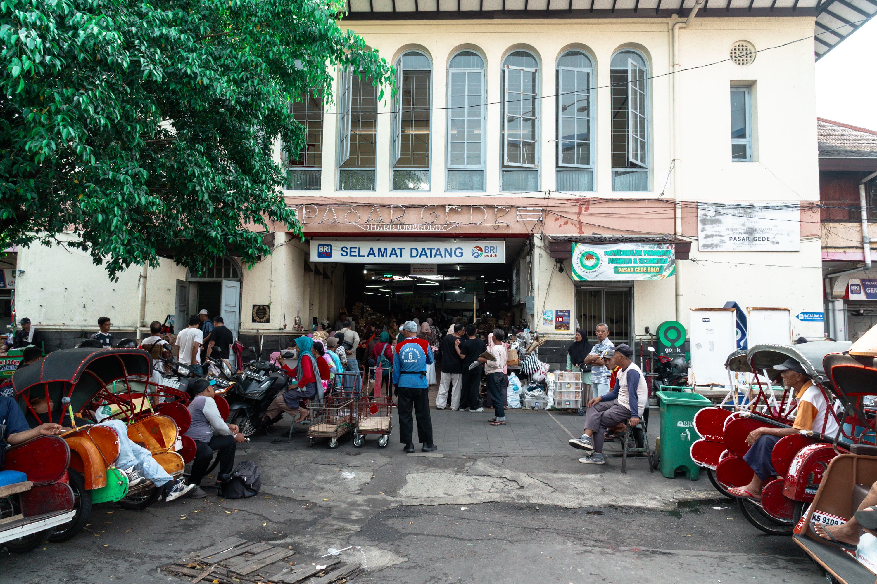 A bustling day at Pasar Gede, a traditional market in Solo, Central Java, Indonesia, with locals and becaks.