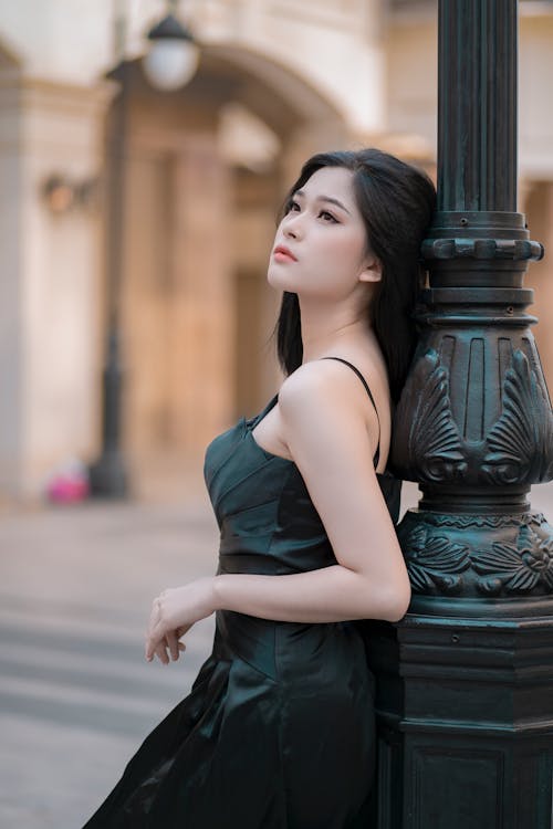 Woman in Black Dress Leaning on Black Steel Post