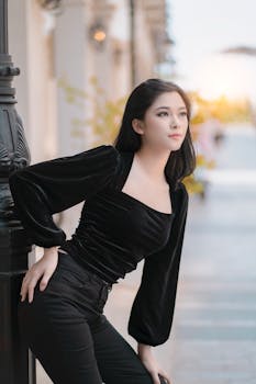 一位别致自信的女人身着时尚黑色服装，在户外摆着姿势