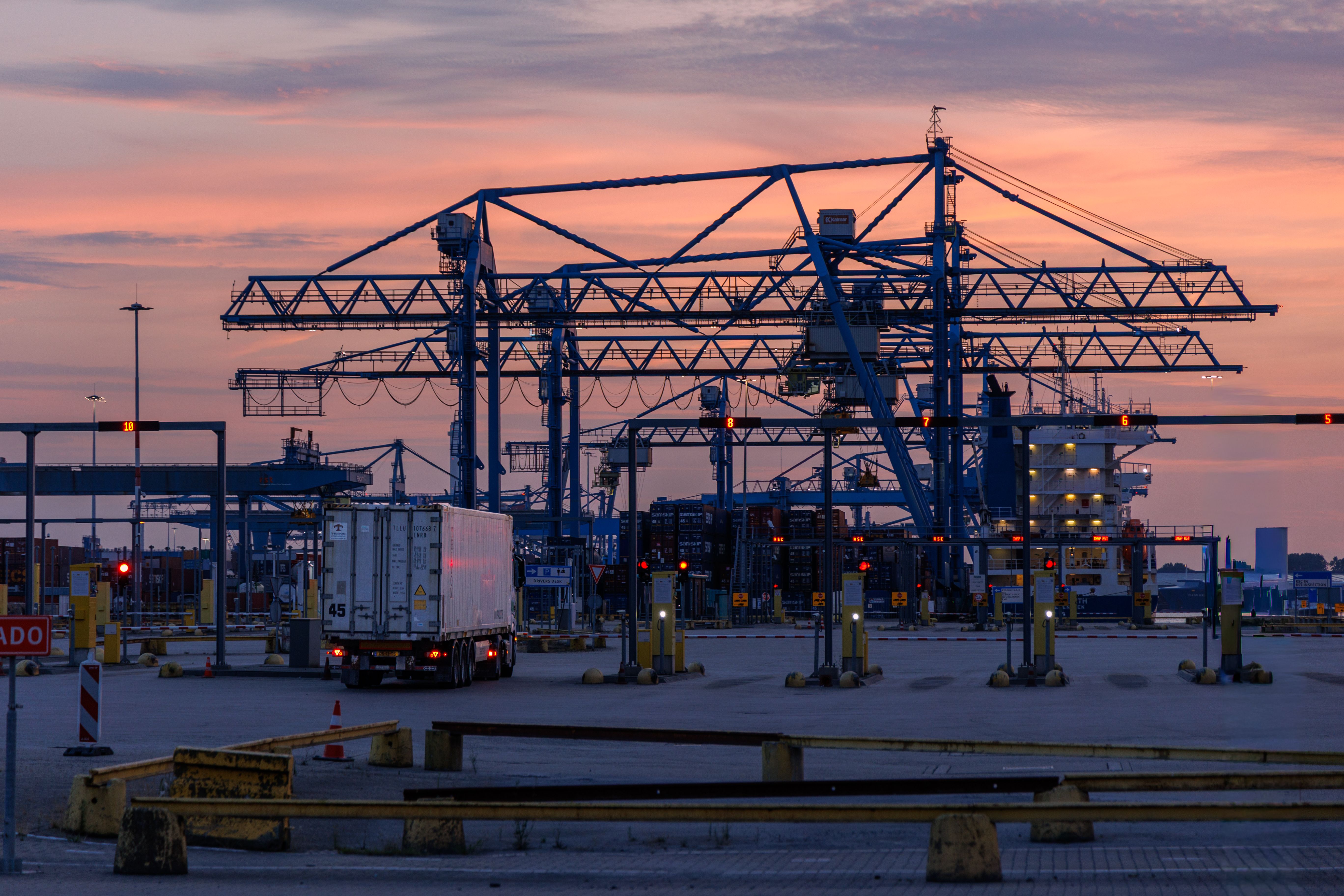 A striking view of cargo cranes at sunset in the bustling Rotterdam shipping port.