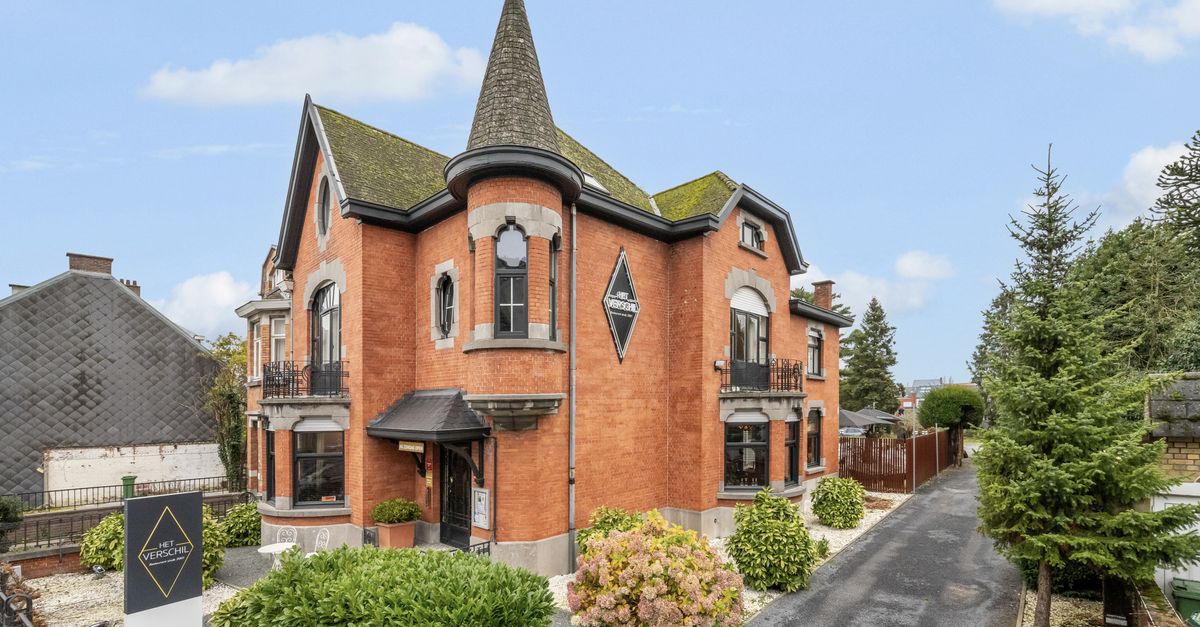 Elegant Victorian-style brick house with lush garden on a bright day.
