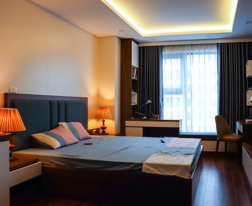 Free A stylish and comfortable bedroom interior illuminated by warm ambient lighting, featuring a bed, desk, and shelves. Stock Photo