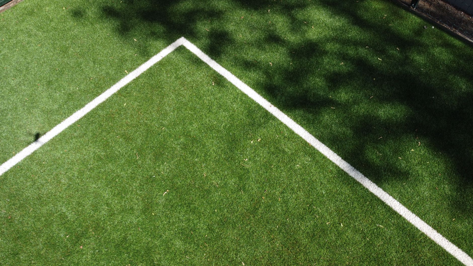 Aerial view of a soccer field corner with shadows on green turf.