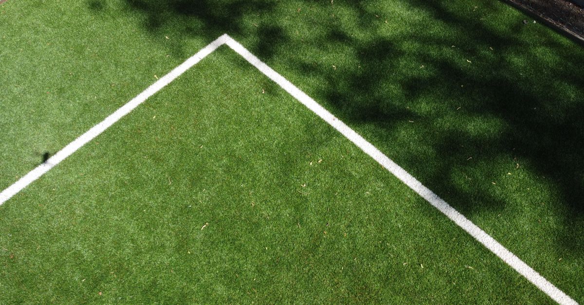 Aerial view of a soccer field corner with shadows on green turf.